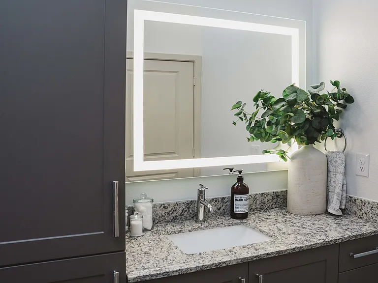 Designer bathrooms with granite countertops and backlit mirrors