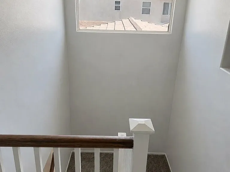 Bright upstairs stairway and landing with a large window providing natural light.
