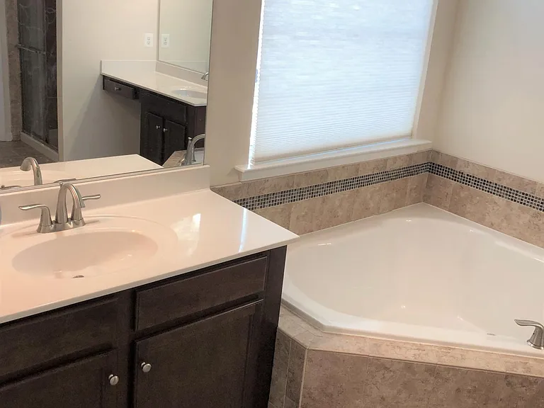 Luxury master bathroom with separate vanities, soaking tub, tiled shower, private toilet, and walk-in closet.
