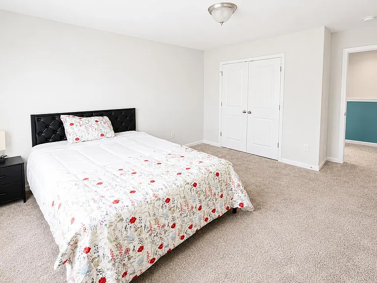 Spacious carpeted bedroom featuring a large window, double-door closet, and ample room for a full/queen bed and storage.
