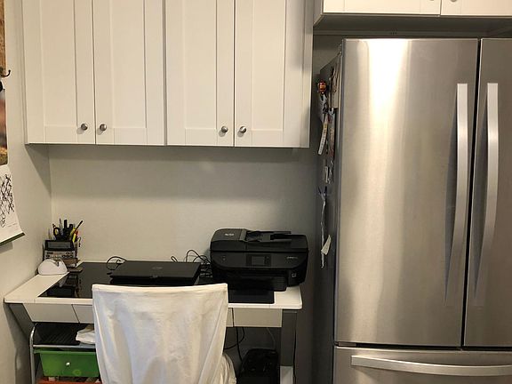 Side table in kitchen area, fridge.