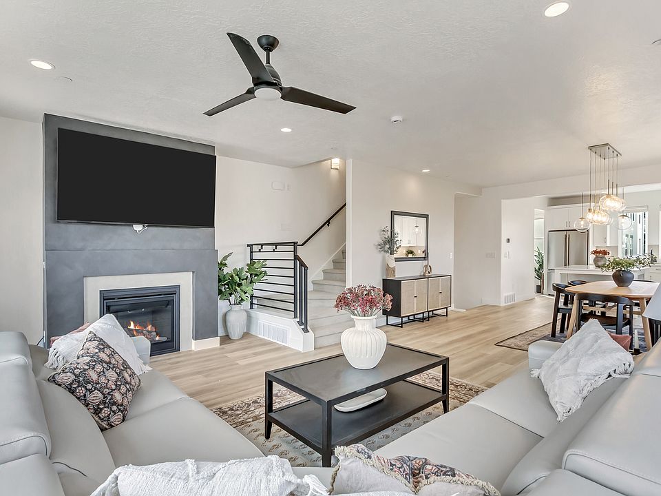 Modern living room with a gray sectional sofa, fireplace, TV, and dining area in an open-plan Major