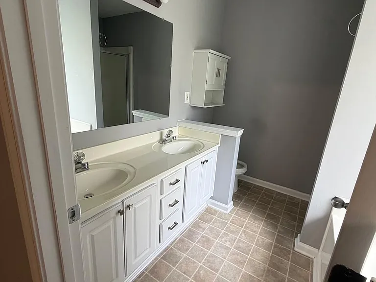 Bright primary bathroom with dual sinks, ample cabinet storage, neutral finishes, and a well-designed layout for added convenience.