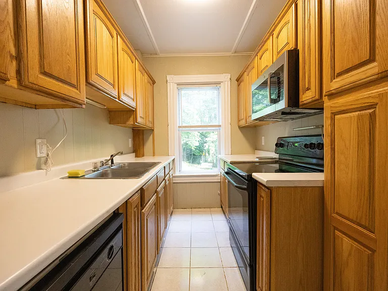 Bright galley kitchen with ample cabinet storage, dishwasher, and microwave