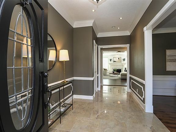 The hardwood and leaded-glass front door has a fresh coat of SW Tricor Black paint, which is a nice contrast color seen throughout this beautifully updated home. The Foyer is a stunning combination of polished porcelain tile (Travertine pattern), cro