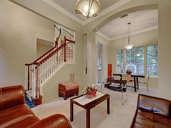 View of the stairs to the second floor and the dining room featuring a large window with view of the mature landscaped yard.
