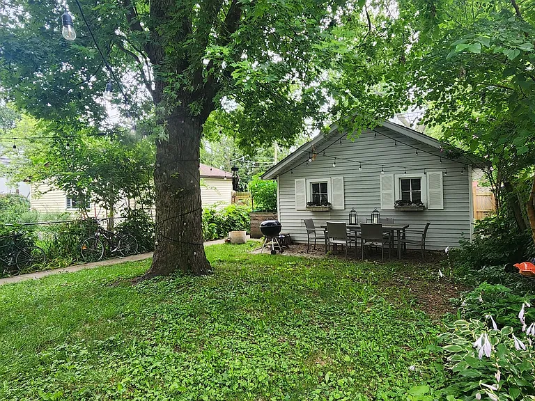 Back yard with patio table, fire pit, charcoal grill and bird sanctuary.