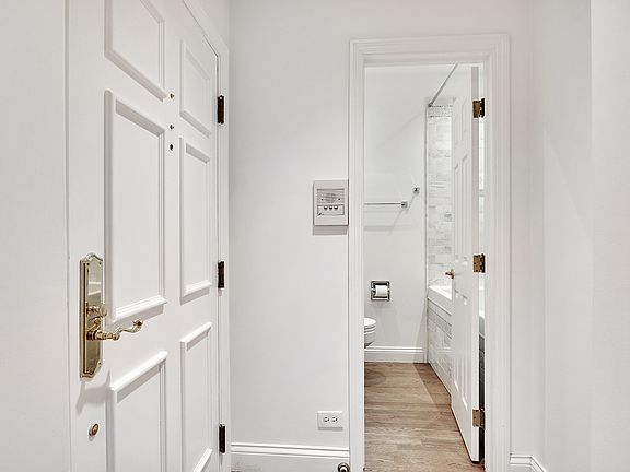 small foyer / front door is on left, hall marble full bath/shower straight ahead, living room behind camera.