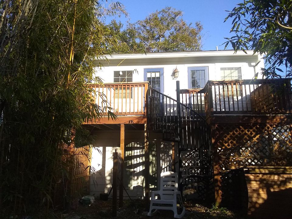 The back of the apartment with the winding stairs leads to a tropical back yard