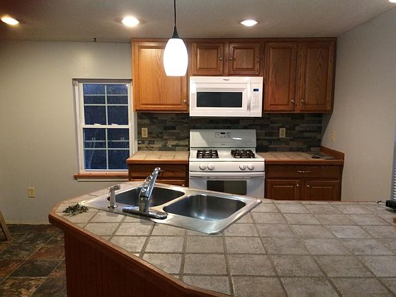 Open kitchen with peninsula island with new stove and microwave.