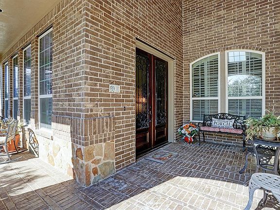 Elegant entrance through the double iron and etched glass wooden doors under the extended front covered patio.