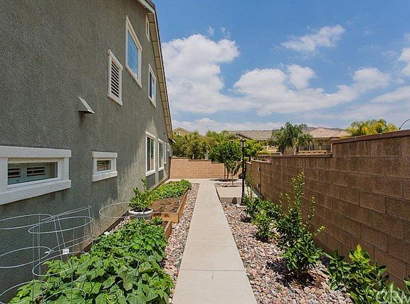 Side yard has raised garden beds and fruit trees.