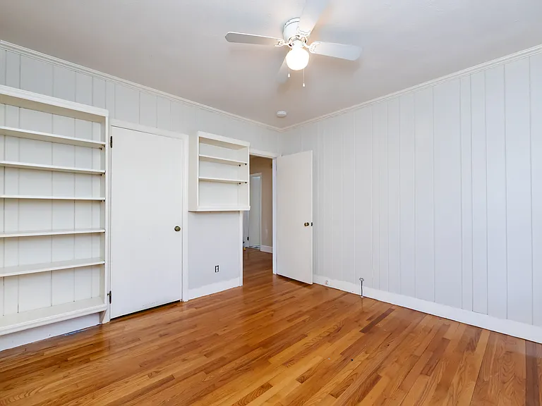 1ST BEDROOM W/ BUILT IN BOOK SHELVES, ENTERS INTO HALLWAY AND KITCHEN, TWO DOORS