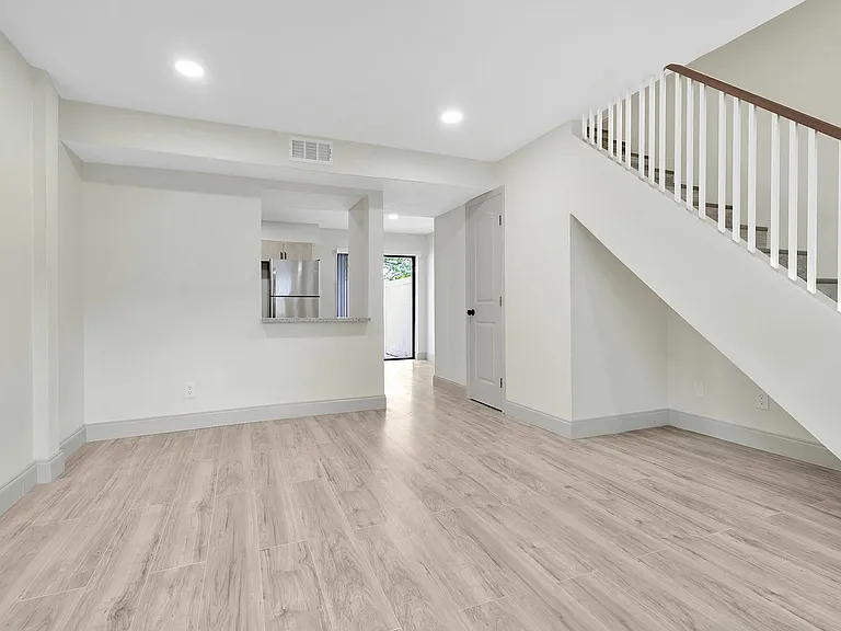 Modern open-concept living space featuring sleek staircase, elegant light wood flooring