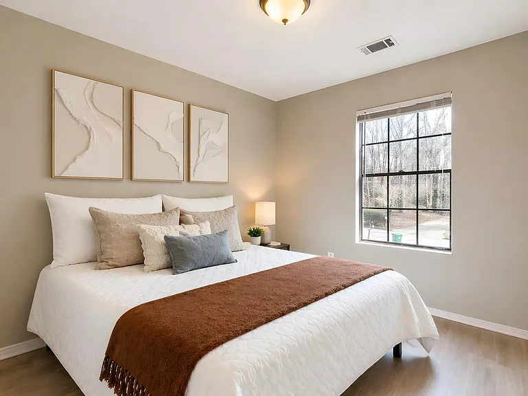 Well-appointed bedroom featuring a comfortable bed, bedside table, and large window for natural light.