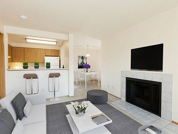 Staged living room with carpeting and fireplace. Kitchen with breakfast seating.