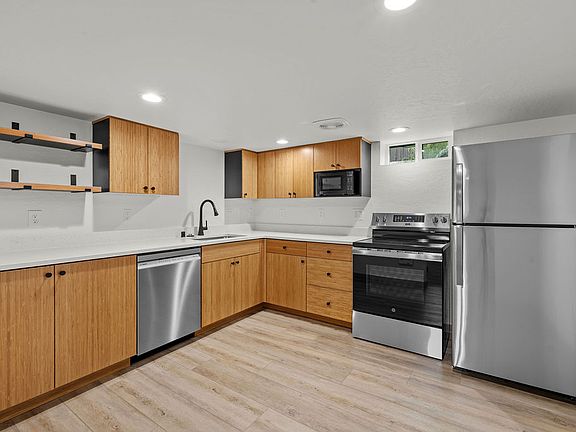 Kitchen with floating shelves, bamboo cabinets, and quartz counters.