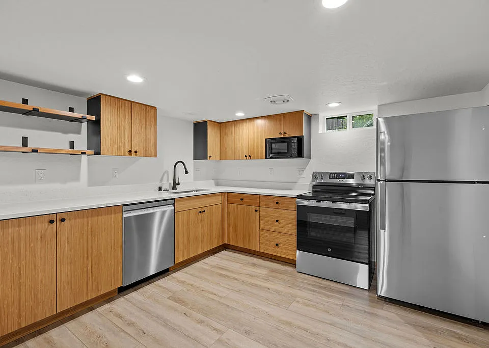 Kitchen with floating shelves, bamboo cabinets, and quartz counters.