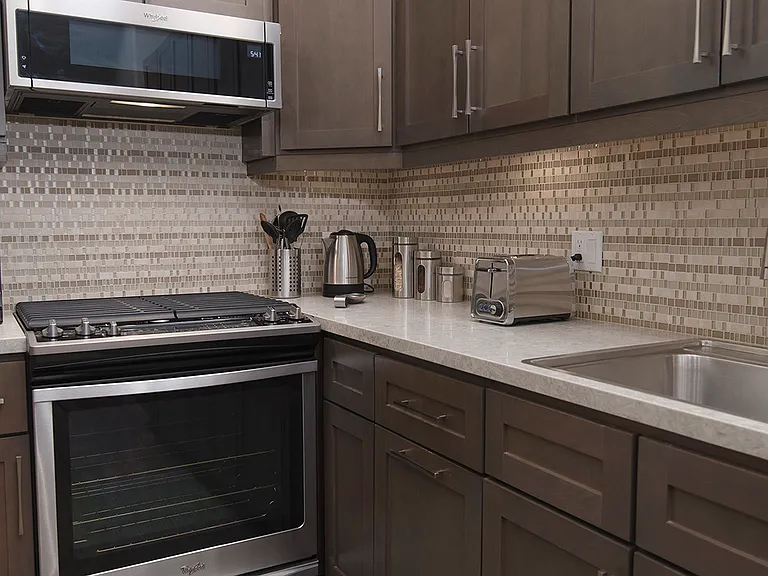 Full kitchen detail with wide dish sink, oven range with cook top and microwave above. Under cabinet lighting.