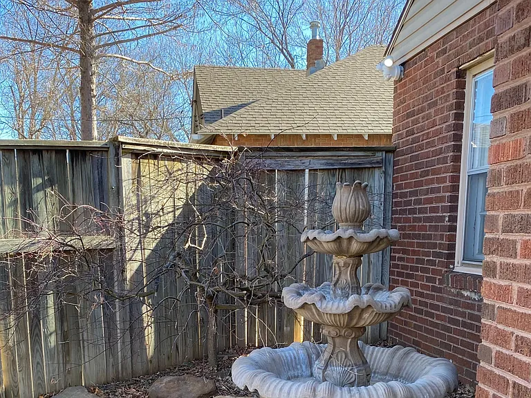 Back of house with fountain and red maple tree