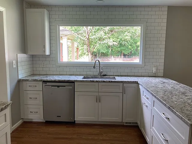 Kitchen with picture window looking out into back yard. Granite countertops. Built -in trash receptacle.