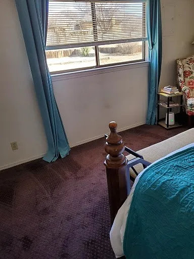 master bedroom window, blinds, drapes, hi-back chair w floral design, wood and wrought iron bedroom set with side tables, footboard...
