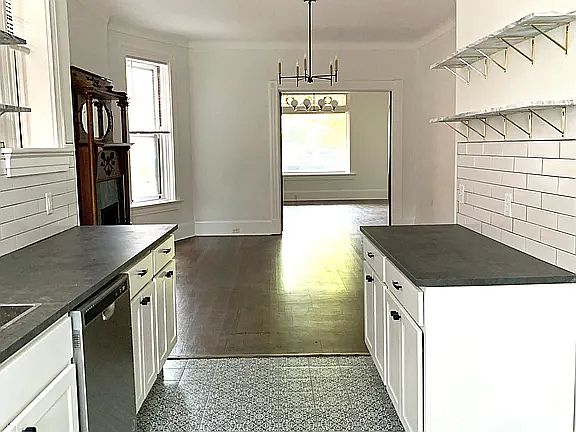 Galley kitchen with floating wall shelves, and new appliances.