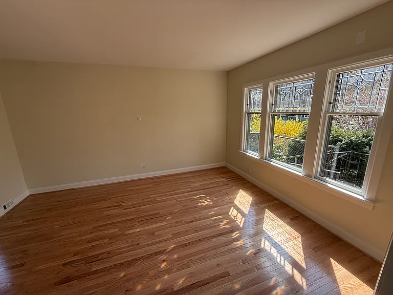 Sunny wide open living room with lovely leaded glass windows that flood the room with light. Brand new solid wood floors.