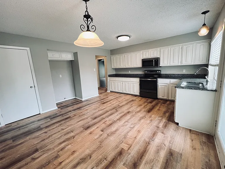Huge kitchen with grey tone granite countertops, deep stainless steel double sinks, nice updated lighting, stainless steel & slate finish appliances and lots of crisp white wood cabinets with an abundance of storage space