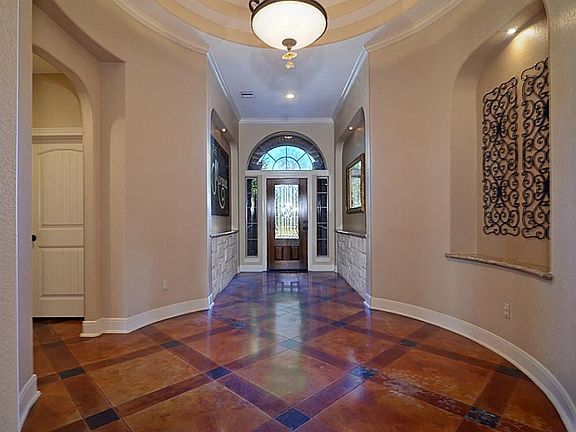 Guests enter the home through an elegant 8-foot tall leaded-glass front door inset between matching side-lights with a transom window above. Notice all the details including the  stone wainscoting