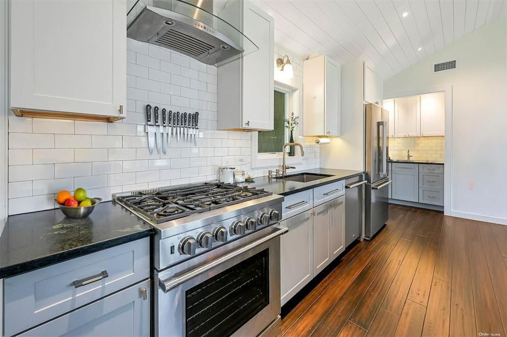  Chefs Kitchen Close up featuring visible vents, premium appliances, wall chimney exhaust hood, vault