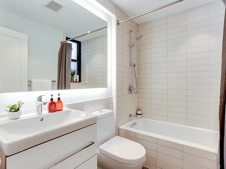 Bright tiled bathrooms with large backlit designer mirror, Hans Grohe chrome fixtures and Villeroy & Boch vanity