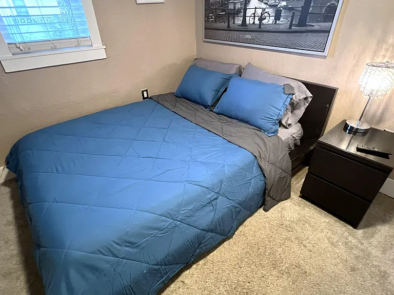 Furnished bedroom with a full bed, nightstand, and window for natural lightan easy, comfortable setup for daily living.