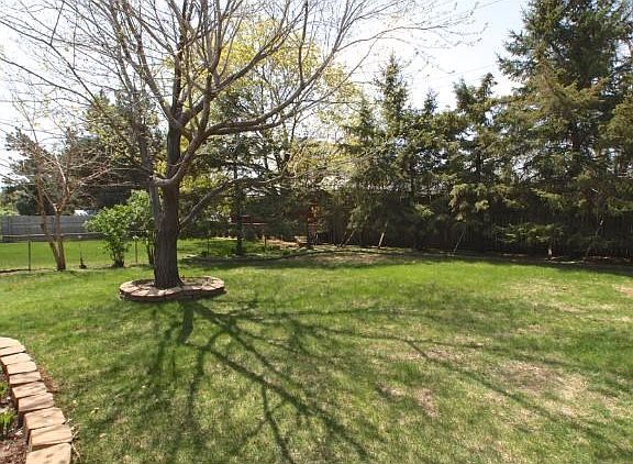 Fenced backyard with nice trees & space to play & entertain.