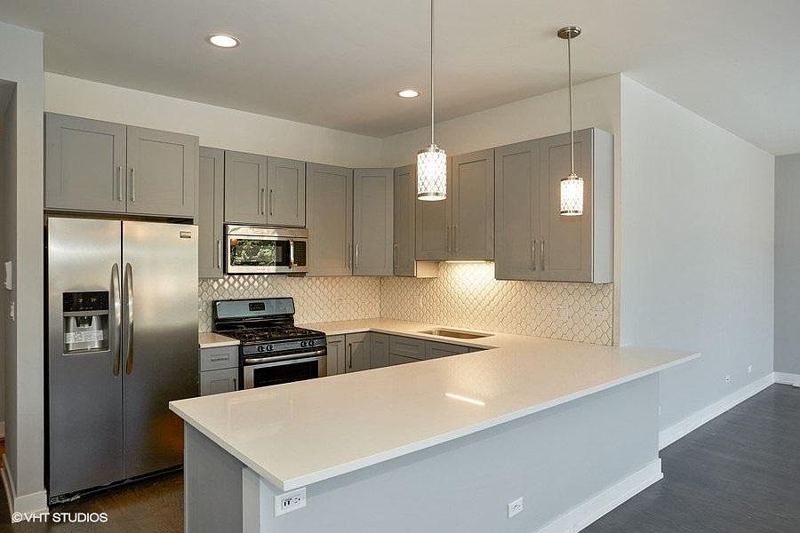 Kitchen with dishwasher, microwave, disposal, and quartz countertop with overhang for seating