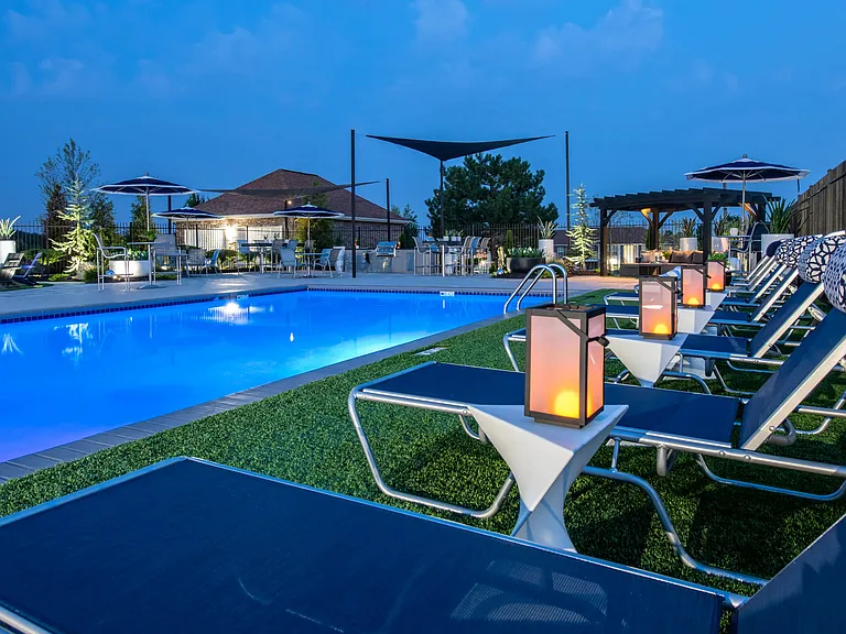 Embrace the vibrant ambiance of the pool deck at night, providing residents an enchanting space for solo relaxation or social enjoyment.
