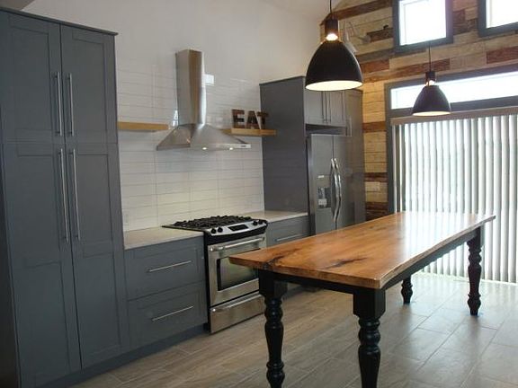 View 2 of kitchen area featuring stainless steel exhaust hood, shelving and 8 1/2' live edge wood island.