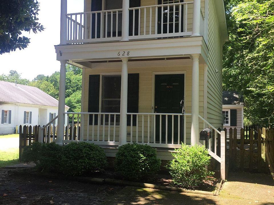 Front of residence, showing driveway, Bedroom deck, and fencing with two gates.