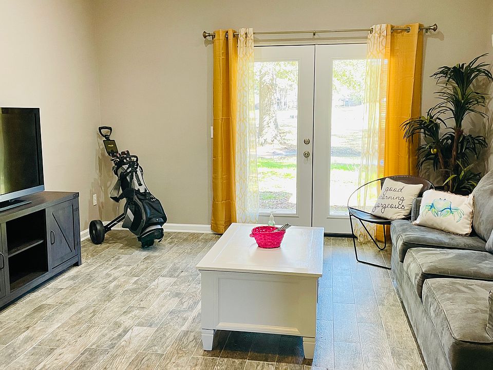 Bright and open living room with double doors leading to covered and furnished patio.