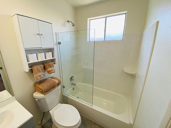Well lit newly renovated bathroom with new tile, elongated & raised toilet, new tub and euro-style glass