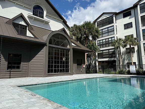 Elegant apartment complex with a pristine swimming pool, surrounded by lush palm trees, offering a luxurious and relaxing atmosphere.