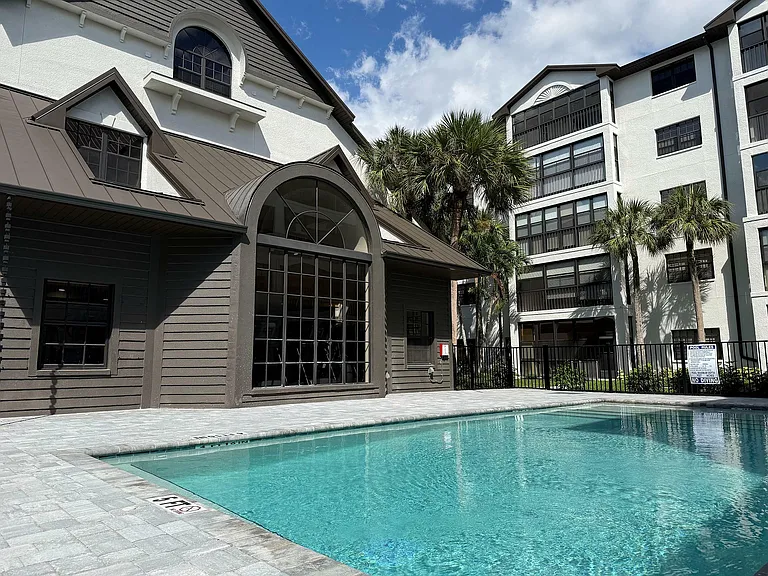 Elegant apartment complex with a pristine swimming pool, surrounded by lush palm trees, offering a luxurious and relaxing atmosphere.