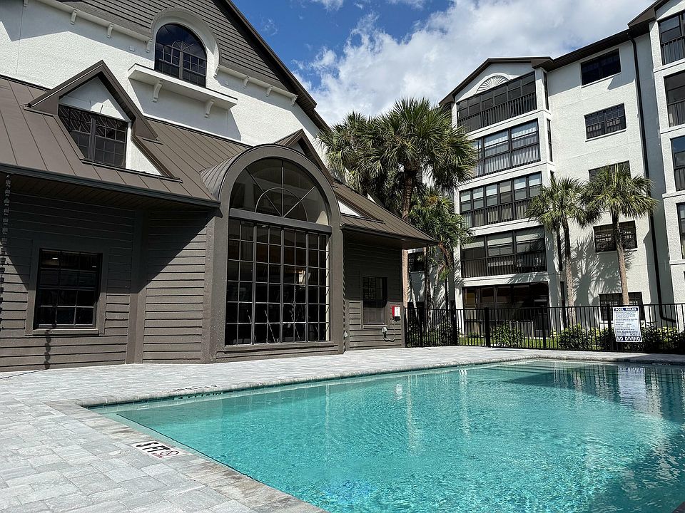 Elegant apartment complex with a pristine swimming pool, surrounded by lush palm trees, offering a luxurious and relaxing atmosphere.