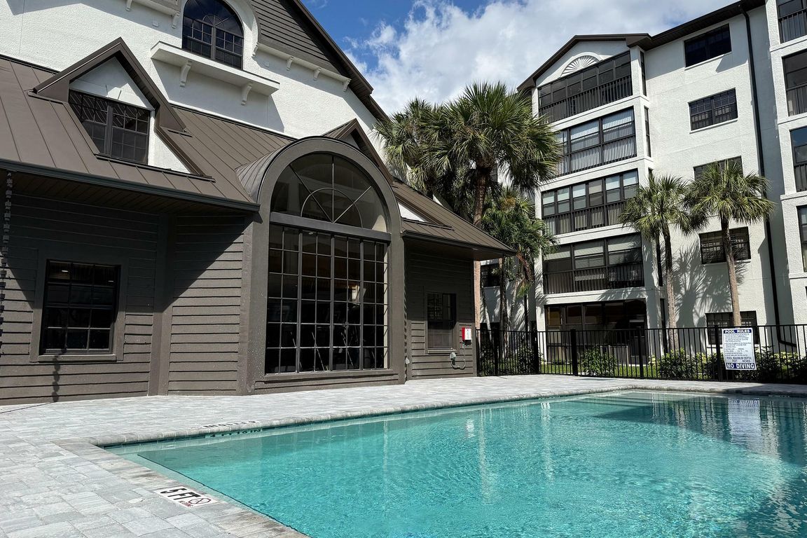 Elegant apartment complex with a pristine swimming pool, surrounded by lush palm trees, offering a luxurious and relaxing atmosphere.