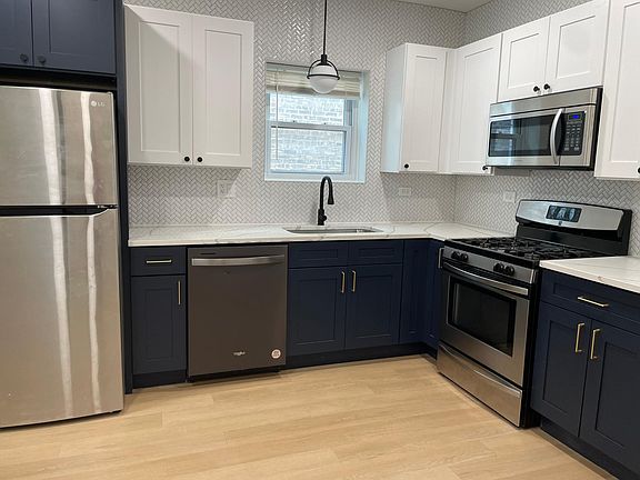 White upper cabinets and navy blue base cabinets with gold hardware pulls