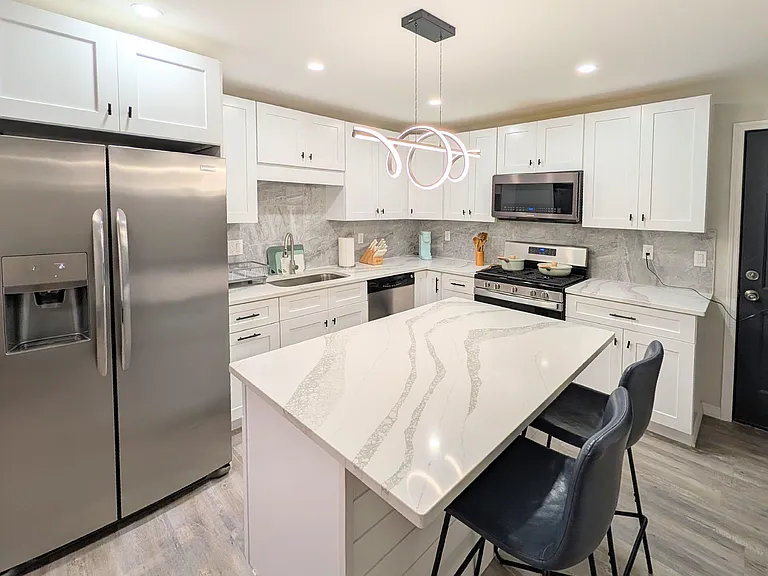 Updated kitchen with stainless steel appliances, ample white cabinetry, and a large island with bar seating.