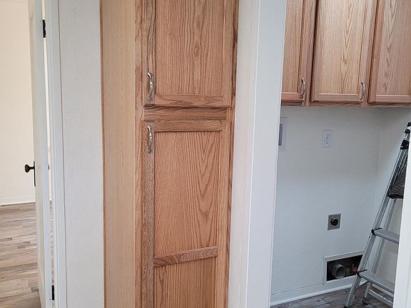 Kitchen pantry cupboard with view to laundry room on right, door to back bedroom on left.