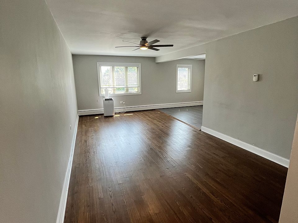 Large living area with ceiling fan and hardwood floors.