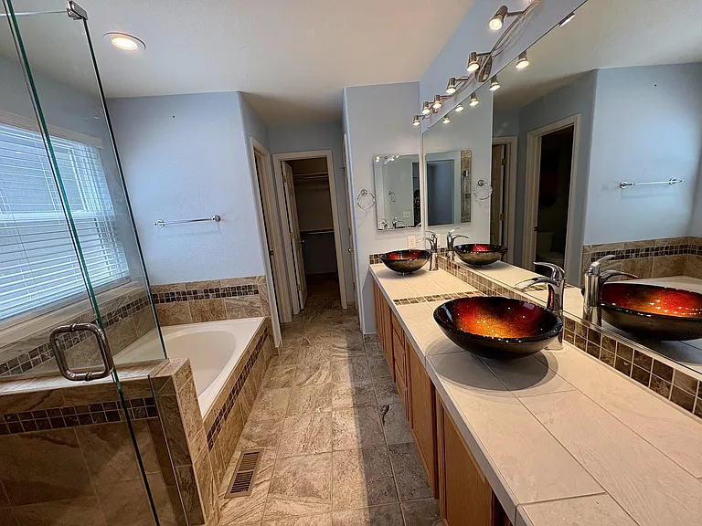 Primary bathroom with double vanity, large soaking tub and shower. Walk-in closet at end of hall.