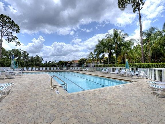 Community Pool & Hot Tub _ Enjoy a resort-style heated pool and relaxing hot tub, surrounded by lush tropical landscaping and ample lounge seating. The spacious sun deck offers plenty of room for sunbathing, reading, or unwinding under shaded umbrellas.